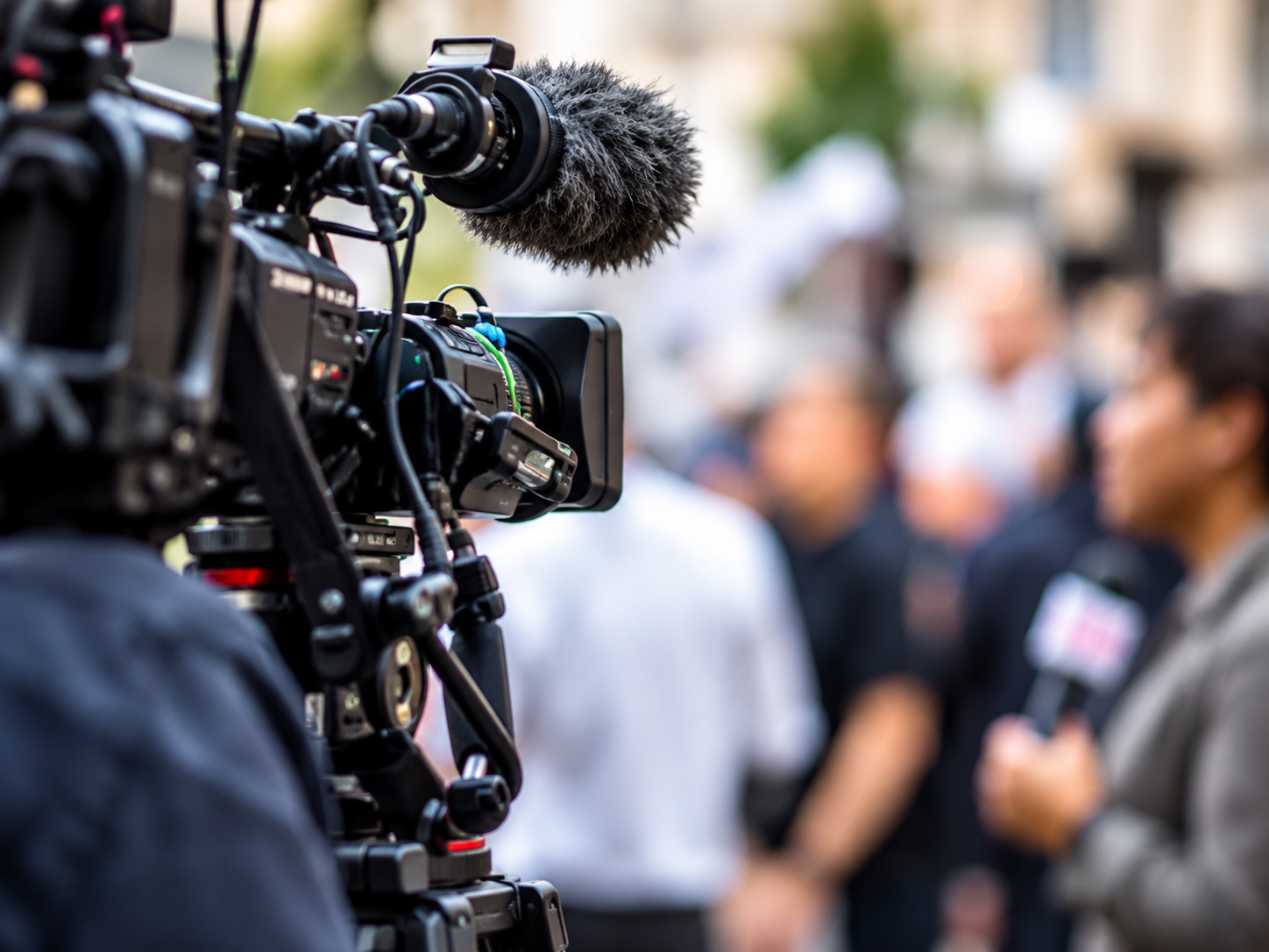 A news camera operator filming in a crowded street